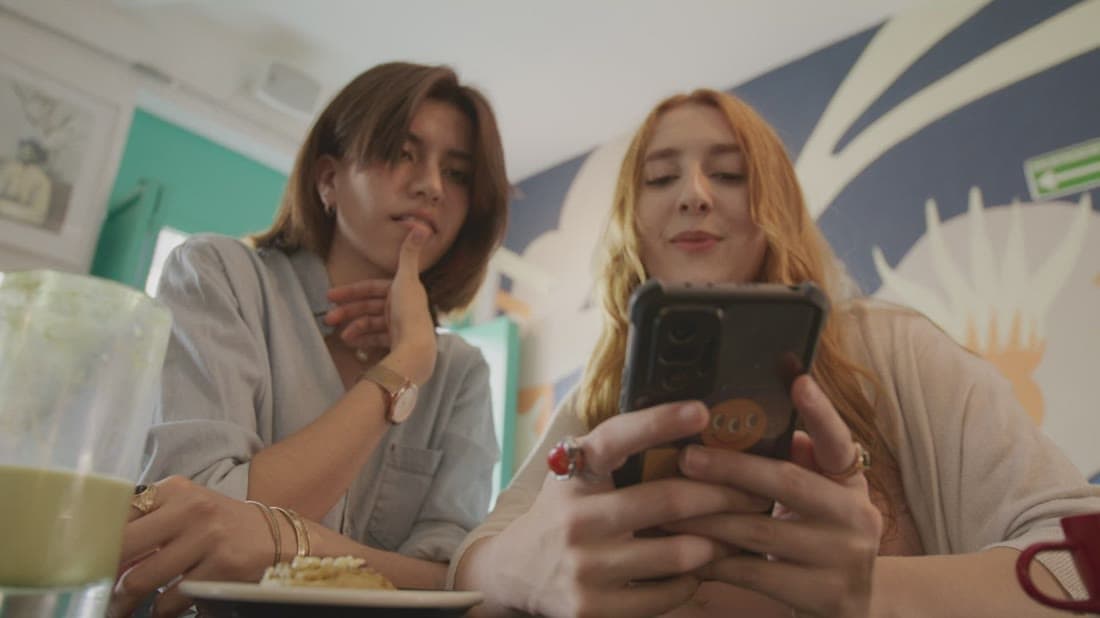 Friends engaging with branded content on social media in a café