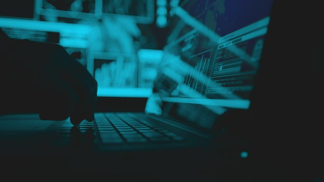Programmer developing an application on a laptop in a dark office