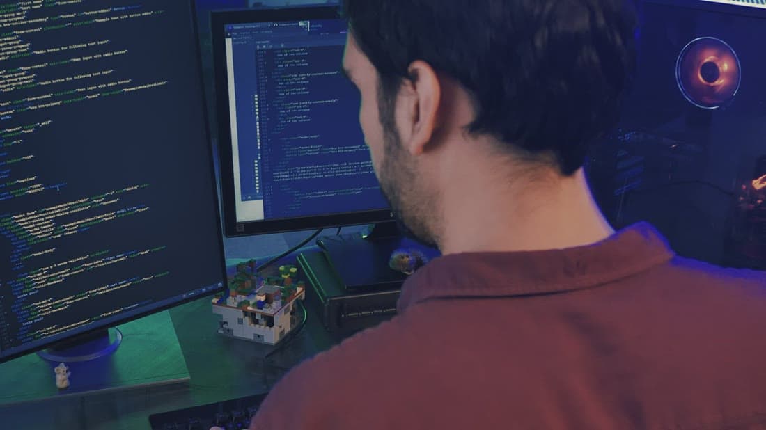 QA engineer reviewing code and test results on a large monitor